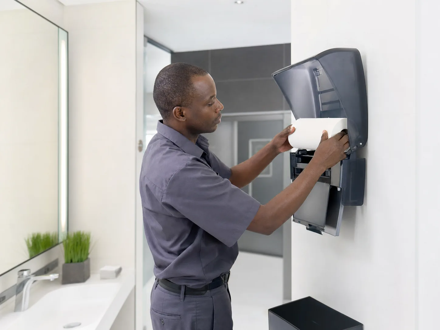 Attendant refilling a commercial paper towel dispenser